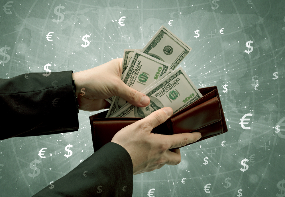 Businessmans hand takes out dollar from a wallet with global and exchange graphic Businessmans hand takes out dollar from a wallet with global and exchange graphic